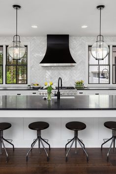 a kitchen with an island and four stools in front of the countertop area