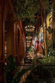 the interior of a restaurant with many tables and plants on the walls, along with potted trees