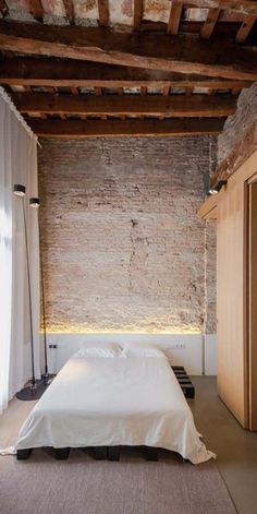 a bed sitting in the middle of a bedroom next to a wall with exposed beams