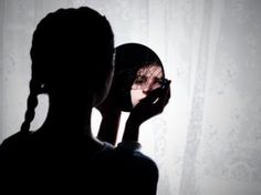 the silhouette of a woman brushing her teeth in front of a mirror