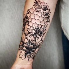 a woman's arm with a bee and flowers tattoo on it