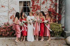 a group of women standing next to each other in front of a building with flowers