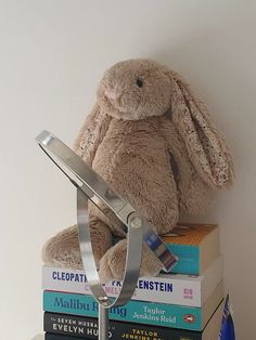 a stuffed rabbit sitting on top of books with a scissor attached to it