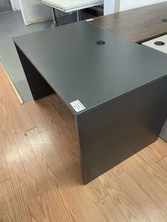 an empty office desk in the middle of a wood floored area with white cabinets