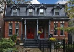 a red brick house with black wrought iron fence and front door on a sunny day