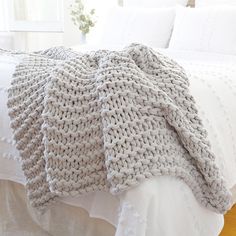 a white bed topped with a blanket and pillows