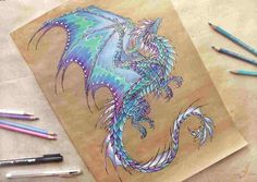 a drawing of a blue dragon on brown paper with colored pencils next to it