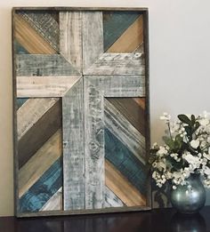 a vase filled with flowers sitting on top of a table next to a wooden cross