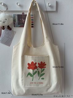 a white bag with red flowers on it hanging from the wall next to a teddy bear