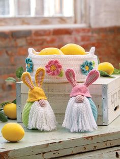 two crocheted bunnies sitting on top of a wooden crate next to lemons