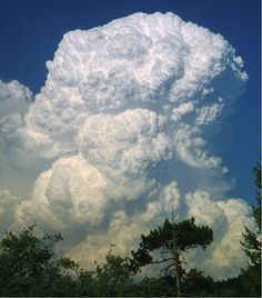 a large cloud is in the sky above some trees