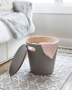 a grey trash can sitting on top of a rug