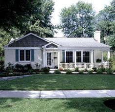 a white house with blue shutters in the front yard