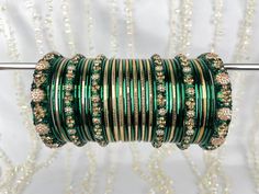 The perfect fusion of tradition and style, designed to elevate your outfit with elegance and charm. This stunning bangle set offers the versatility you've been searching for, as it can be tailored to adorn either one hand or both, ensuring that you shine in any setting. This set includes a total of 24 colored bangles, carefully selected to complement a wide range of outfits and moods. 2 stunning Kara bangles add a touch of mystique and allure to your ensemble, and 4 Churi bangles provide a captivating contrast to your look. To maintain a balance we've also included 11 plain insert bangles, offering a clean and classic finish to your overall aesthetic. Adjustable Green Jewelry For Diwali, Fusion Style Green Bracelet For Festivals, Fusion Style Green Bracelets For Festivals, Green Fusion Style Bracelet For Festivals, Green Bracelets For Ceremonial And Festival Occasions, Green Bollywood Bracelets For Festivals, Green Bollywood Bracelets For Diwali, Festive Green Bangle As Gift, Festive Green Bracelets For Celebration