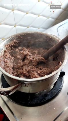 a large pot on top of a stove with a wooden spoon sticking out of it