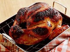 a roasted turkey in a roasting pan being held by a person's hand