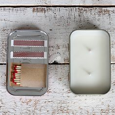 an open matches box next to a matchbox filled with matches on a white wooden surface