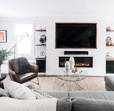 a living room with two couches and a television mounted on the wall above it