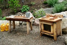 two wooden stoves sitting next to each other on top of a gravel ground near rocks