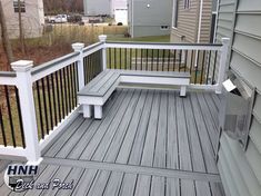 a white bench sitting on top of a wooden deck next to a fence and house