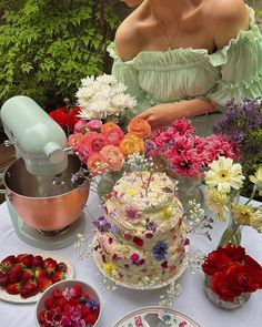 a woman sitting in front of a table filled with cakes and flowers