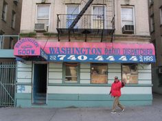 a man walking down the street in front of a radio dispatcher's shop