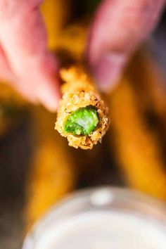 fried asparagus on a stick being held up by someone's hand with the words fried asparagus above it