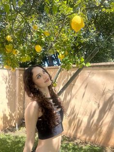 a woman standing in front of a lemon tree