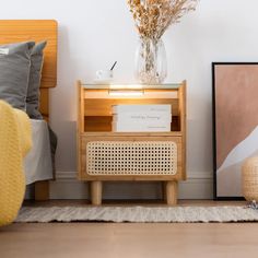 a bed room with a neatly made bed next to a night stand and a vase filled with flowers