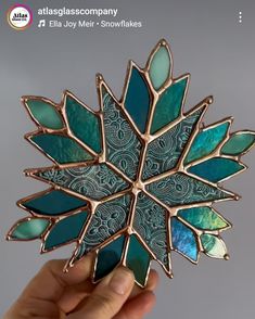 a hand holding a blue and green broochle