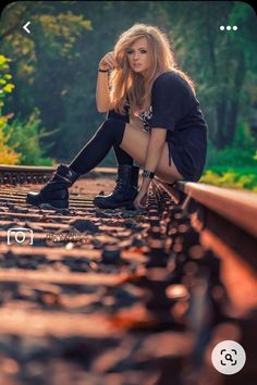 a woman is sitting on train tracks with her legs crossed and looking at the camera