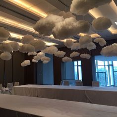 the tables are covered with white linens and clouds hanging from the ceiling above them