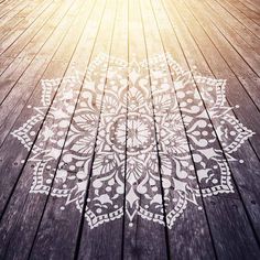 a wooden floor with an intricate design painted on the wood and sun shining in the background