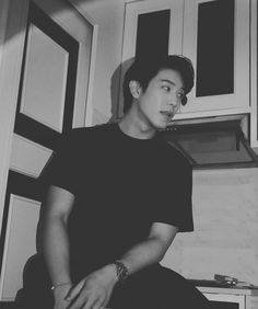 black and white photograph of a young man sitting on the floor in front of cabinets