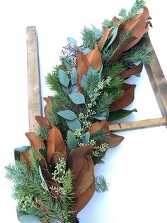 a wooden ladder decorated with greenery and pine cones