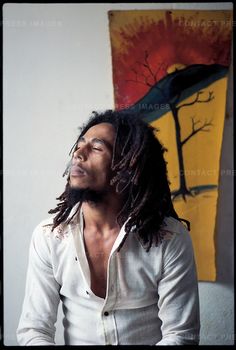 a man with dreadlocks looking up in front of a painting