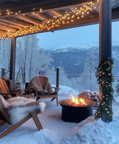 a fire pit in the middle of a snow covered deck with chairs and lights on it