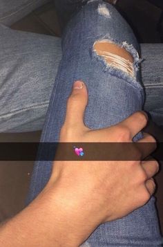 a person with their hand on the leg of someone's jeans that has been ripped