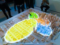 a group of people standing around a model of a city