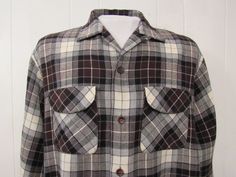 "Vintage 1960s button down shirt. Made of black, gray, brown and white plaid Rayon/wool. Has two chest flap pockets, button front, top button loop and button cuffs. Made by Acrallama. Size large. Actual measurements are: 48\" around the chest 48\" at the waist 18\" shoulder seam to shoulder seam 24.5\" shoulder seam to end of cuff 29\" overall length In very good condition." Brown Collared Flannel Shirt With Buttons, Classic Brown Flannel Shirt With Buttons, Retro Brown Shirt With Pockets, Vintage Collared Flannel Shirt With Button Closure, Vintage Collared Flannel Shirt With Buttons, Vintage Plaid Shirt With Pockets, Retro Collared Flannel Shirt With Pockets, Vintage Brown Flannel Shirt With Button Closure, Vintage Brown Flannel Shirt With Buttons