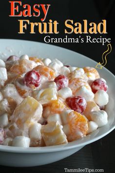 a white bowl filled with fruit salad on top of a black tablecloth next to an orange and cranberry sauce