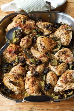 a pan filled with chicken and vegetables on top of a wooden table