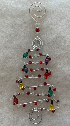 a christmas tree made out of glass beads and silver wire with red, green, yellow and blue beads