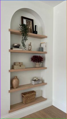 some shelves with vases, books and pictures on them in the corner of a room