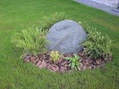 a large rock sitting in the middle of some grass