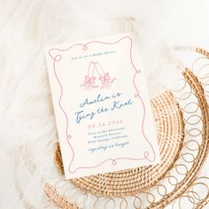 a white card with pink and blue designs on it sitting on a wicker basket