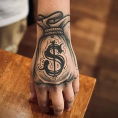 a person's hand with a tattoo on it and a dollar sign in the jar