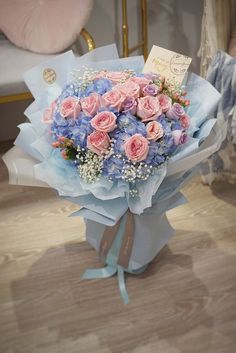 a bouquet of pink and blue flowers sitting on top of a wooden floor next to a bed