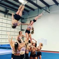 a group of women standing on top of each other in front of a gym floor