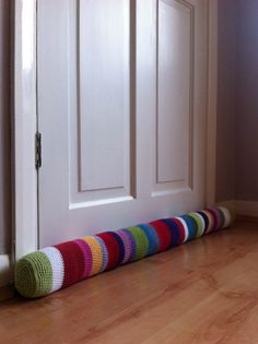 a multicolored knitted tube sitting on the floor in front of a door